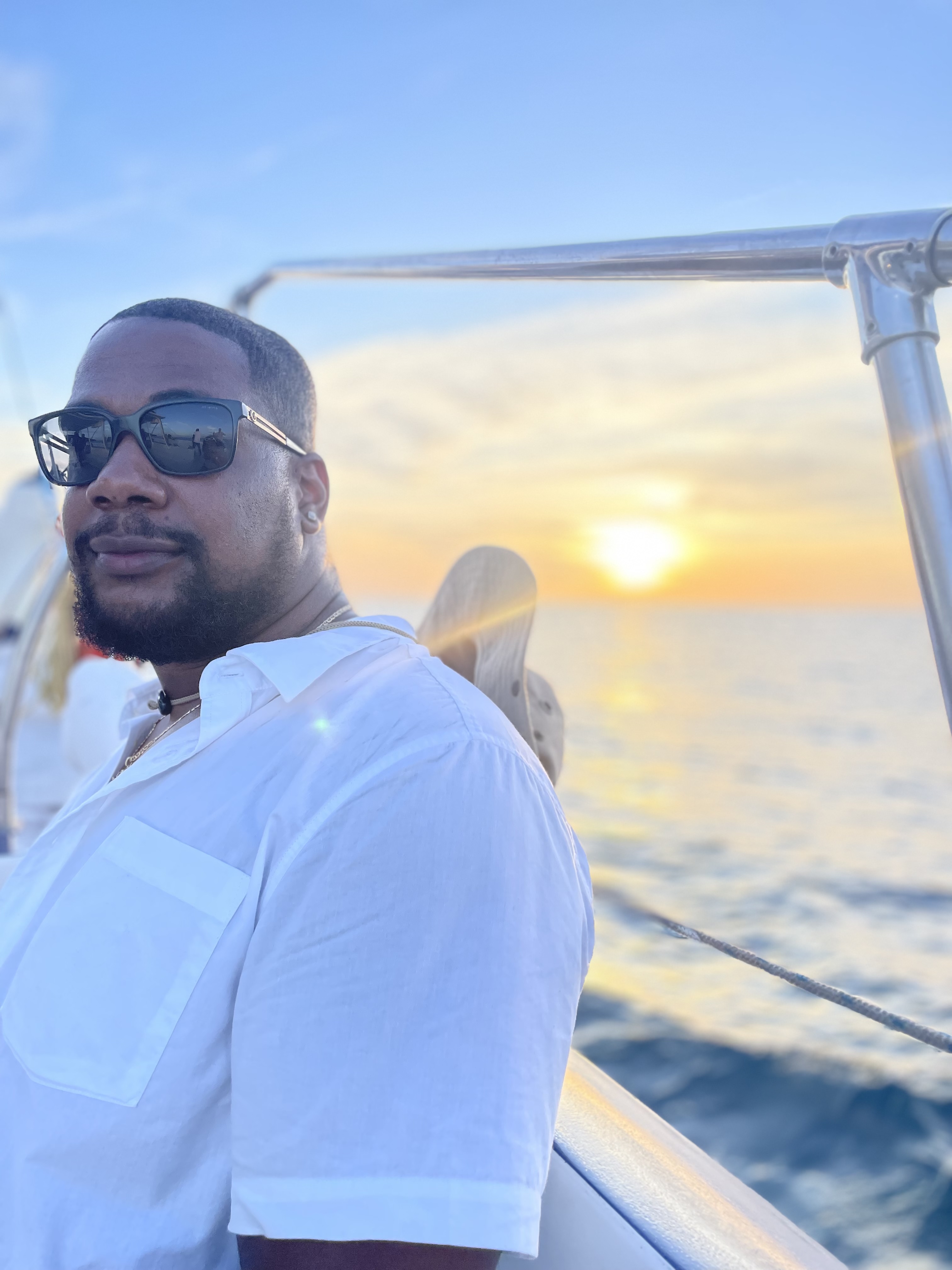 Andrew Quash sitting on boat with sunset in background